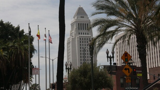 A street view with a tall white building, palm trees, and traffic signs including a speed limit sign. - Metro Plaza Hotel (Los Angeles)
