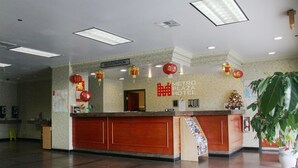 A hotel reception area with a registration desk, a large potted plant, and a sign indicating the hotel's name. - Metro Plaza Hotel (Los Angeles)