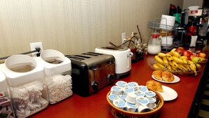 A breakfast buffet setup with toasters, plates of food, and condiments. - Metro Plaza Hotel (Los Angeles)