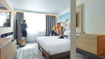 Relax in comfort with a large bed, dresser, and TV, surrounded by a cozy atmosphere.