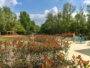 A park with a playground, seating area, and trees.