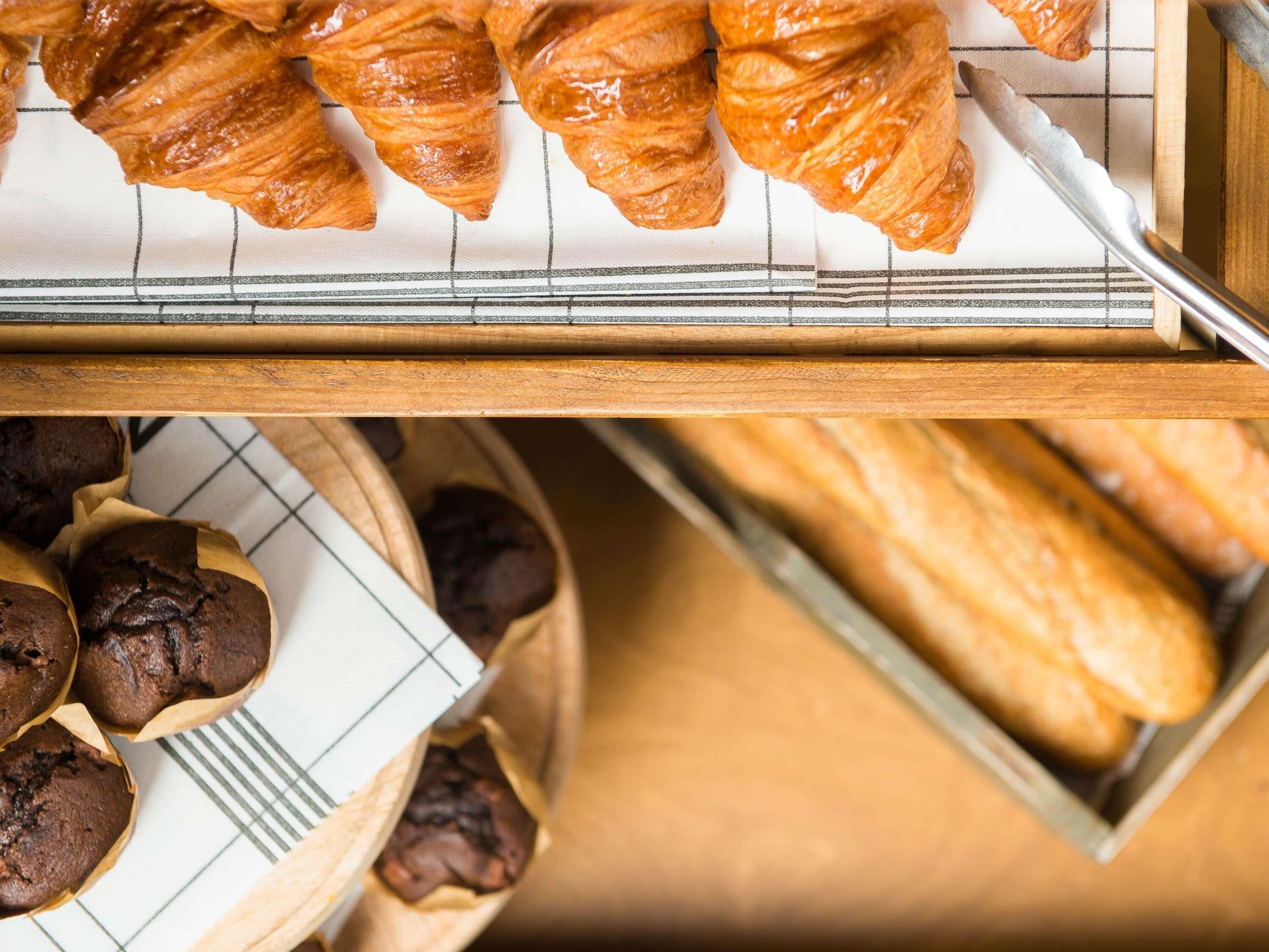 Une assiette de croissants et de muffins sur une surface en bois.