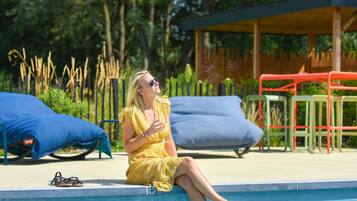 Een seizoensgebonden buitenzwembad en ligstoelen