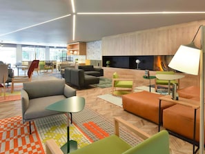 A modern lounge area with sofas, tables, and a fireplace. - Novotel Wavre Brussels East Hotel (Wavre)