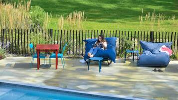 Un espace aménagé au bord de la piscine, avec un canapé bleu, une table rouge et des chaises bleues.