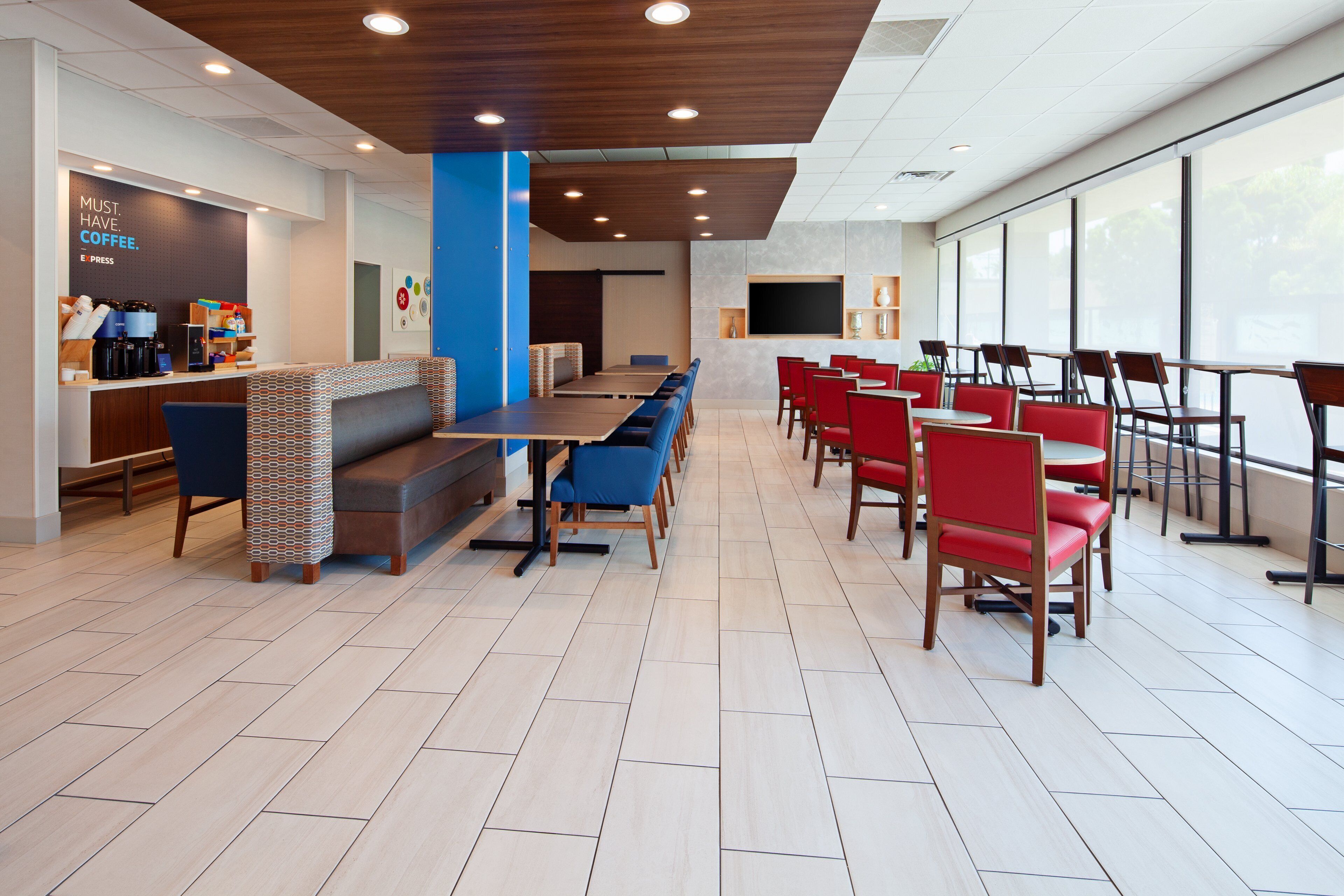 A modern cafe with a long counter, seating area, and large windows.