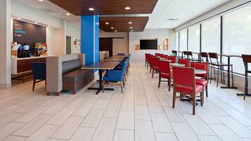A modern cafe with a long counter, seating area, and large windows.