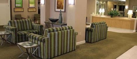 A hotel lobby with striped armchairs, a reception desk, and framed artwork on the walls.