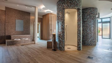 Ein modernes Badezimmer mit Holzboden, Ziegelwand und Duschbereich mit Mosaikfliesen.