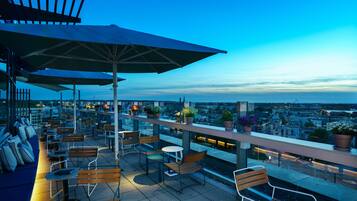 Enjoy panoramic city views from this rooftop terrace, featuring comfortable seating and lush greenery.