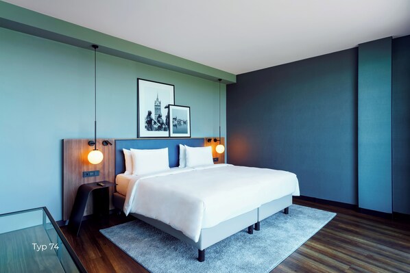 A modern hotel room with a large bed, a bedside table, and a nightstand.