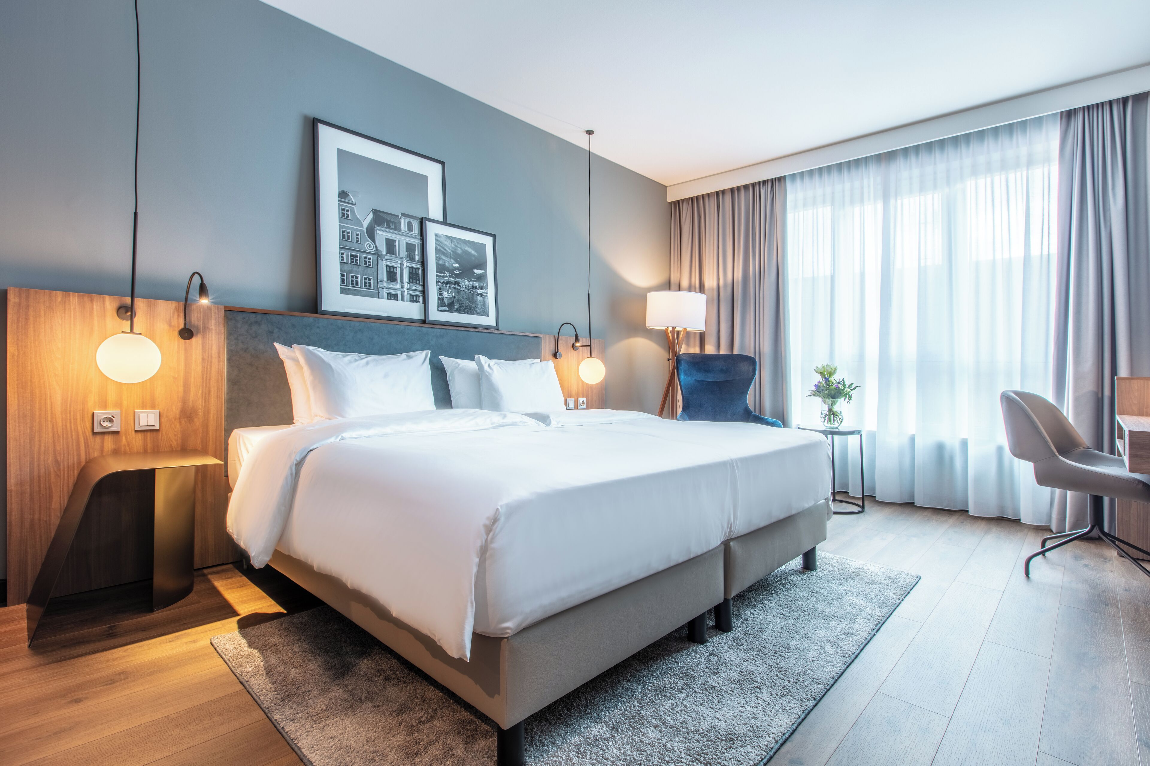 Habitació d'hotel moderna amb un llit gran, vàries làmpades de nit, un escriptori i una cadira.