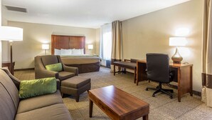 A hotel room with a bed, a sofa, a desk, and a chair. - Quality Inn Summerville - Charleston (Summerville)