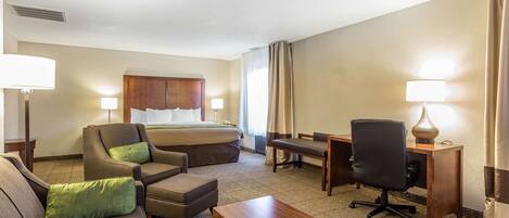 Ein Hotelzimmer mit Bett, Sofa, Schreibtisch und Stuhl.