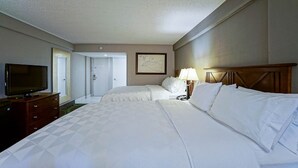 A hotel room with two beds, a television on a dresser, and a framed picture on the wall. - Holiday Inn Manhattan at the Campus by IHG (Manhattan)