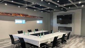 A conference room with a long table, chairs, water bottles, a flat-screen TV, and a fireplace. - Holiday Inn Manhattan at the Campus by IHG (Manhattan)