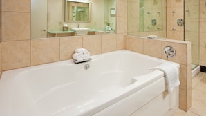 A modern bathroom with a large bathtub, a glass shower enclosure, and a vanity with a mirror. - Holiday Inn Manhattan at the Campus by IHG (Manhattan)