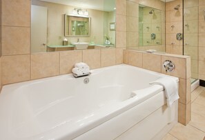 A modern bathroom with a large bathtub, a glass shower enclosure, and a vanity with a mirror.