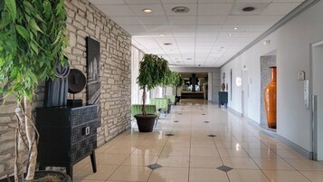 Un pasillo con pared de piedra, plantas en macetas y piso de baldosas.