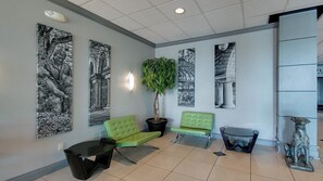 A lobby with a green sofa, a black coffee table, a potted plant, and wall art. - Holiday Inn Manhattan at the Campus by IHG (Manhattan)