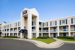 A multi-story hotel with a central tower, balconies, and a parking lot.