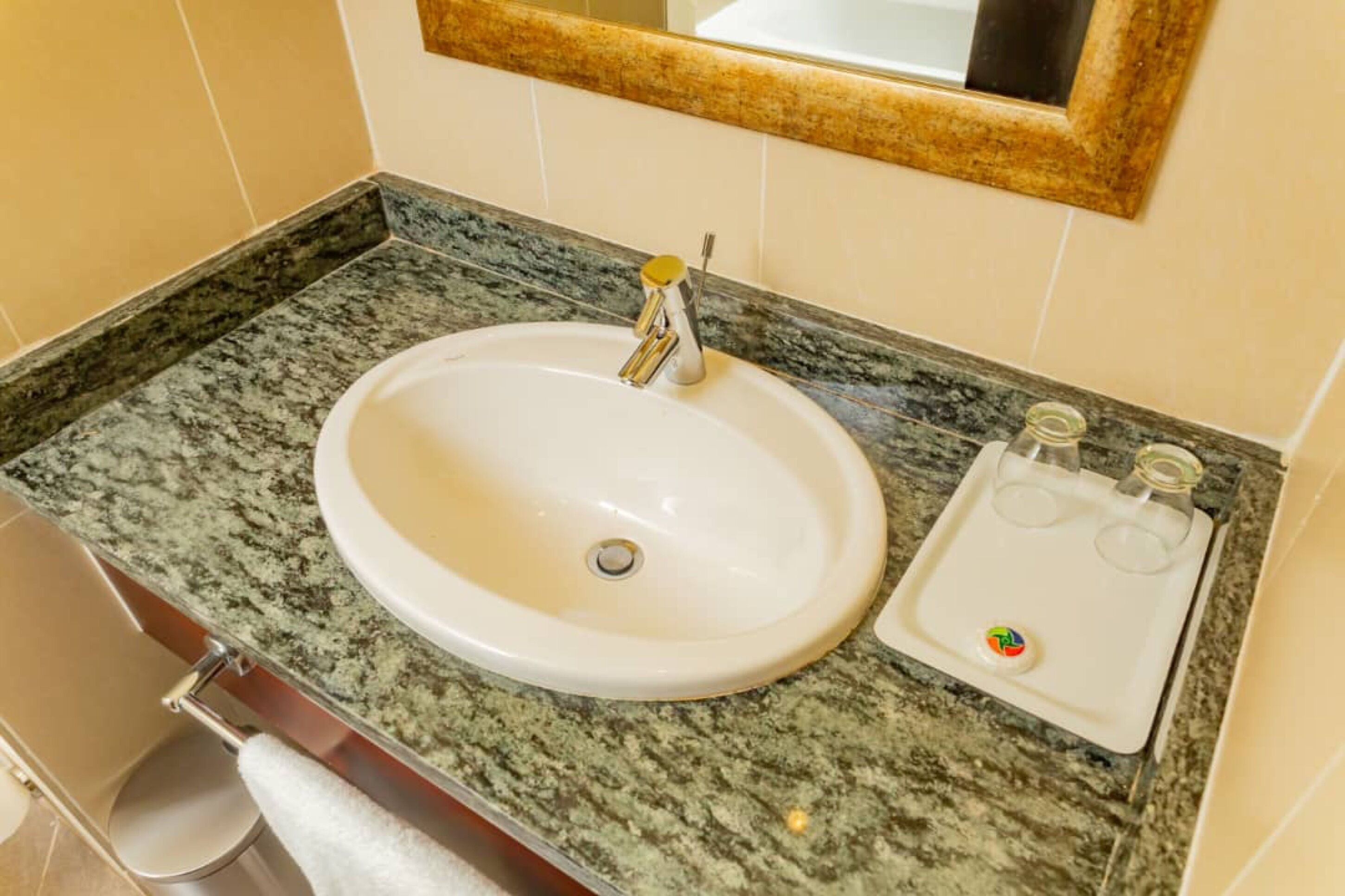 A bathroom with a white sink, granite countertop, and a mirror above it.