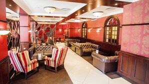 Un hall con un sofá y sillones a rayas rojas y blancas, un sofá de cuero capitonado y un sillón a rayas.