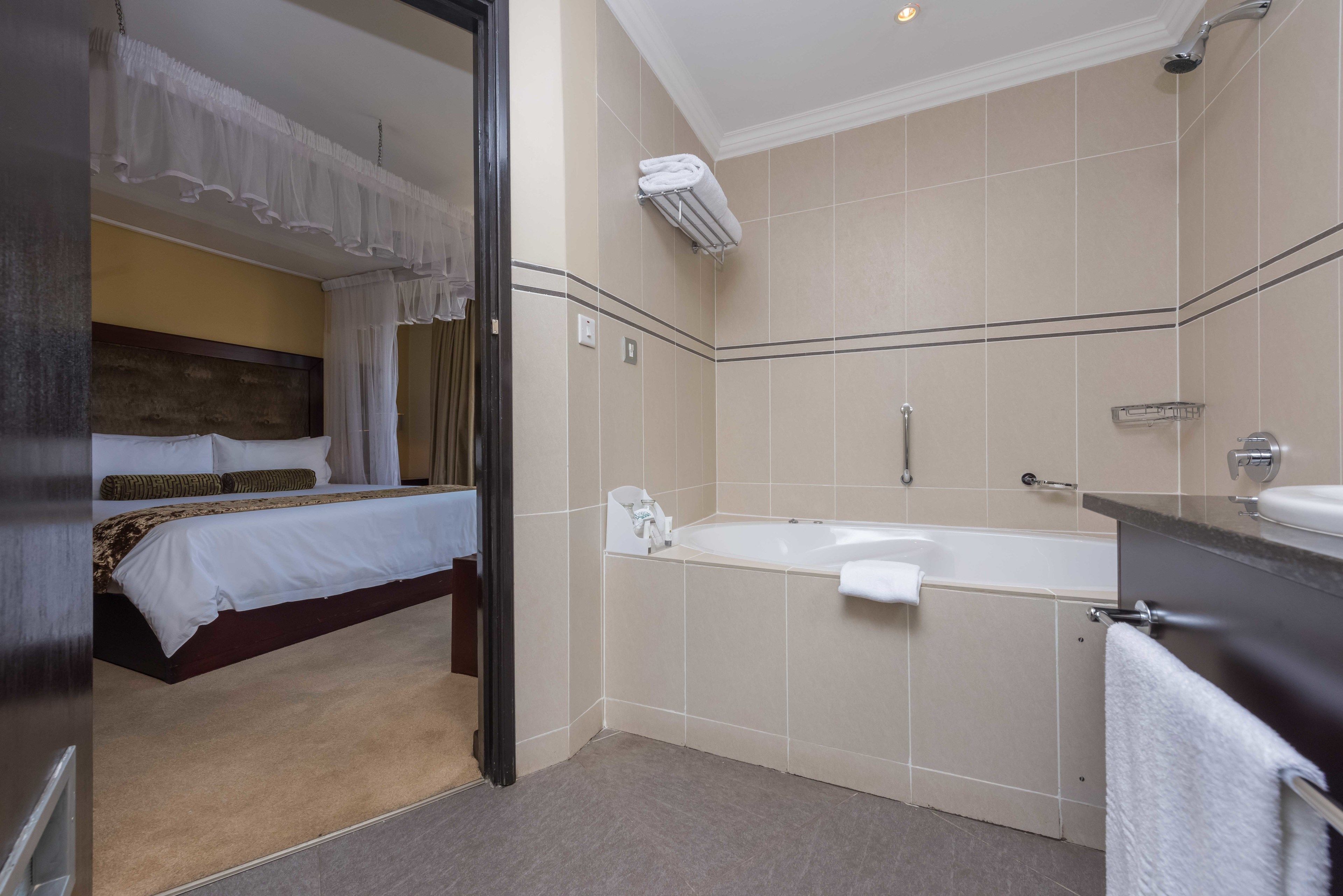 Una habitación de hotel con una cama, un baño con bañera y ducha.