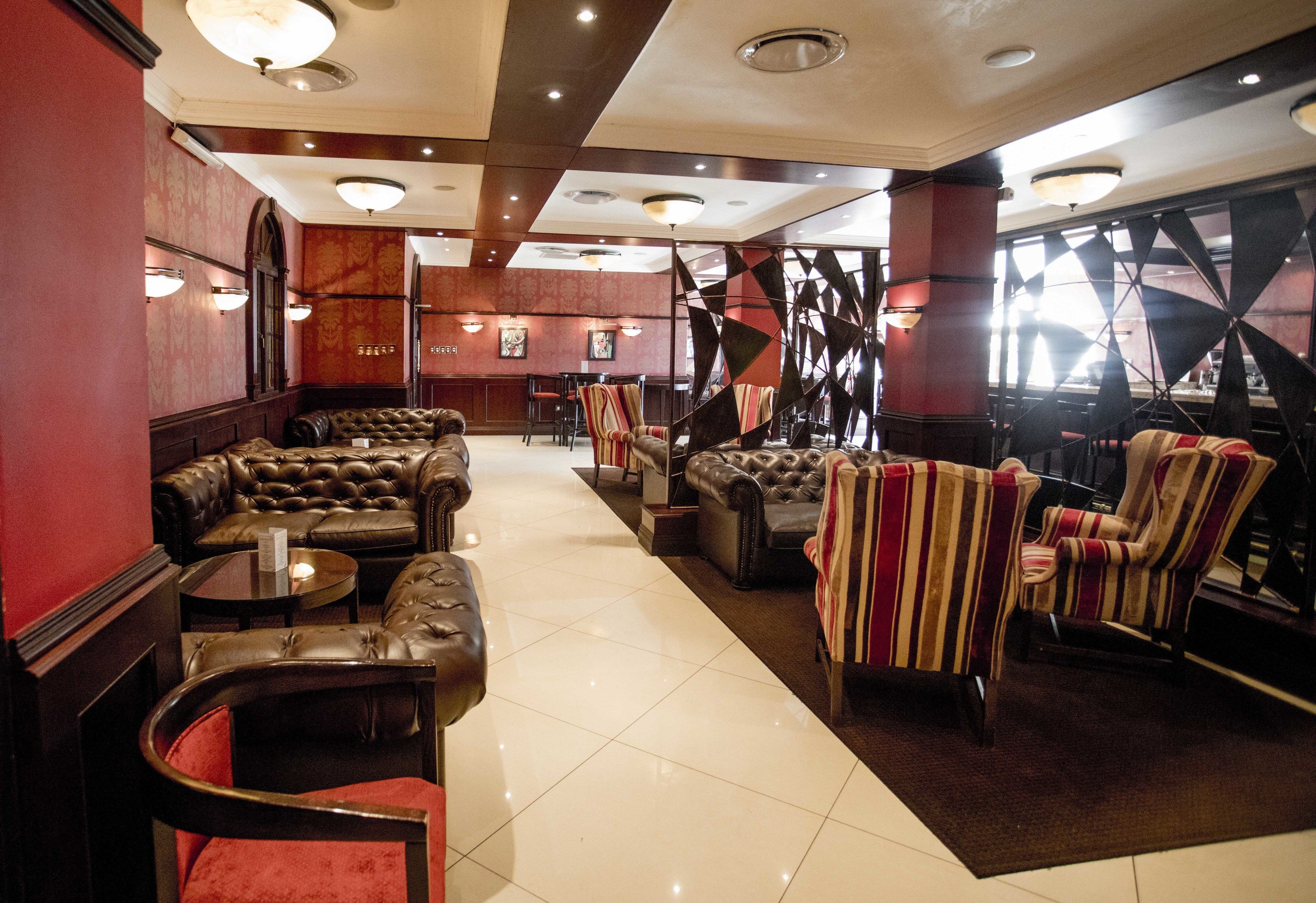 A lobby with leather sofas, striped armchairs, and a staircase with a geometric design.