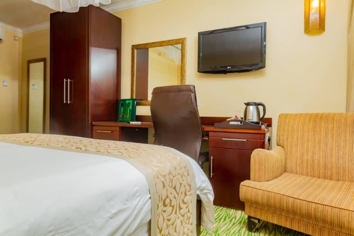Una habitación de hotel con una cama, un escritorio con silla, televisión y sofá.