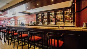 Zona de bar con varios taburetes y una barra bien surtida.