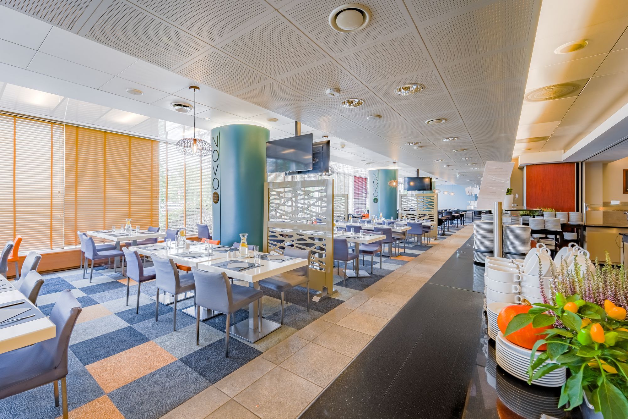 Un restaurante moderno con una barra larga, varias mesas y diferentes opciones de asiento.