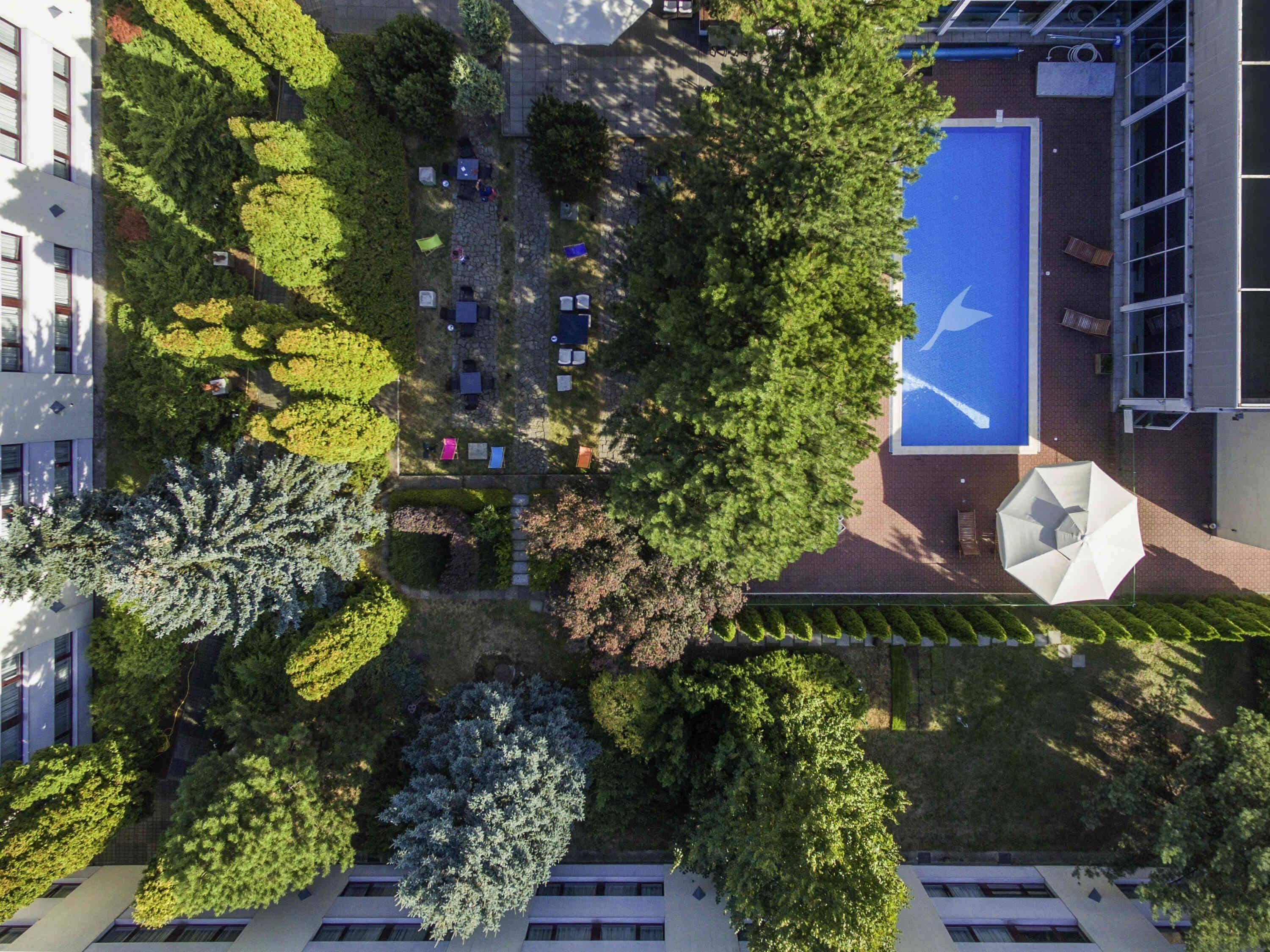 An aerial view of a courtyard with a blue sports court, surrounded by trees and buildings.