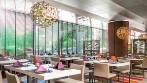 A modern restaurant with large windows, multiple tables, and hanging spherical light fixtures.