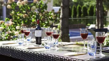A table set outdoors with wine glasses and a bottle, surrounded by greenery.