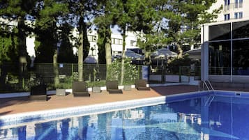 Una piscina al aire libre de temporada, sillones reclinables de piscina
