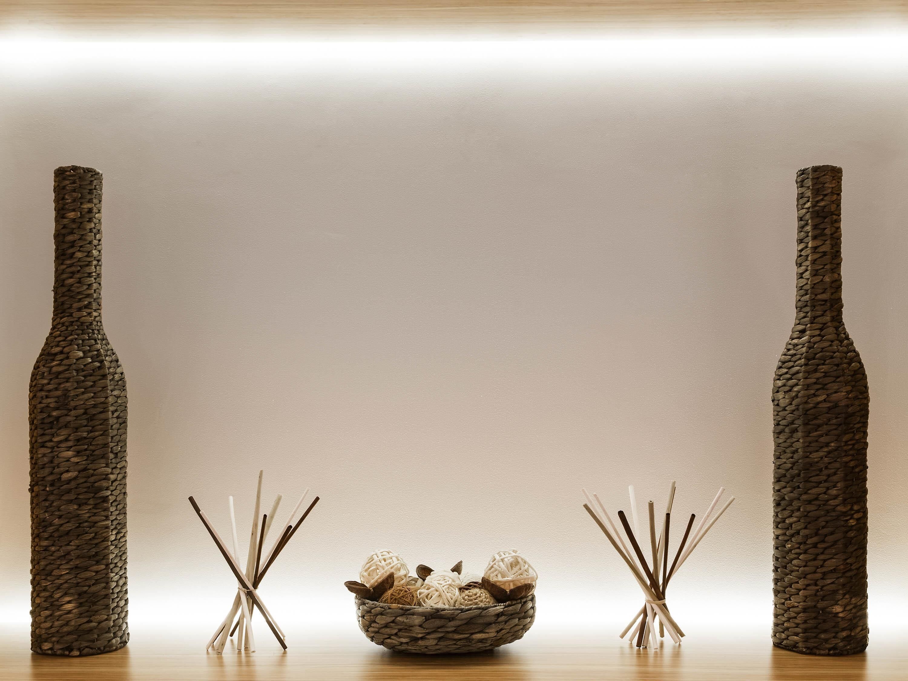 A room with two tall, textured vases on either side of a central woven basket containing decorative items.