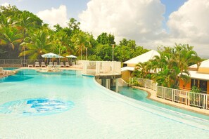 Una piscina al aire libre, sombrillas, sillones reclinables de piscina