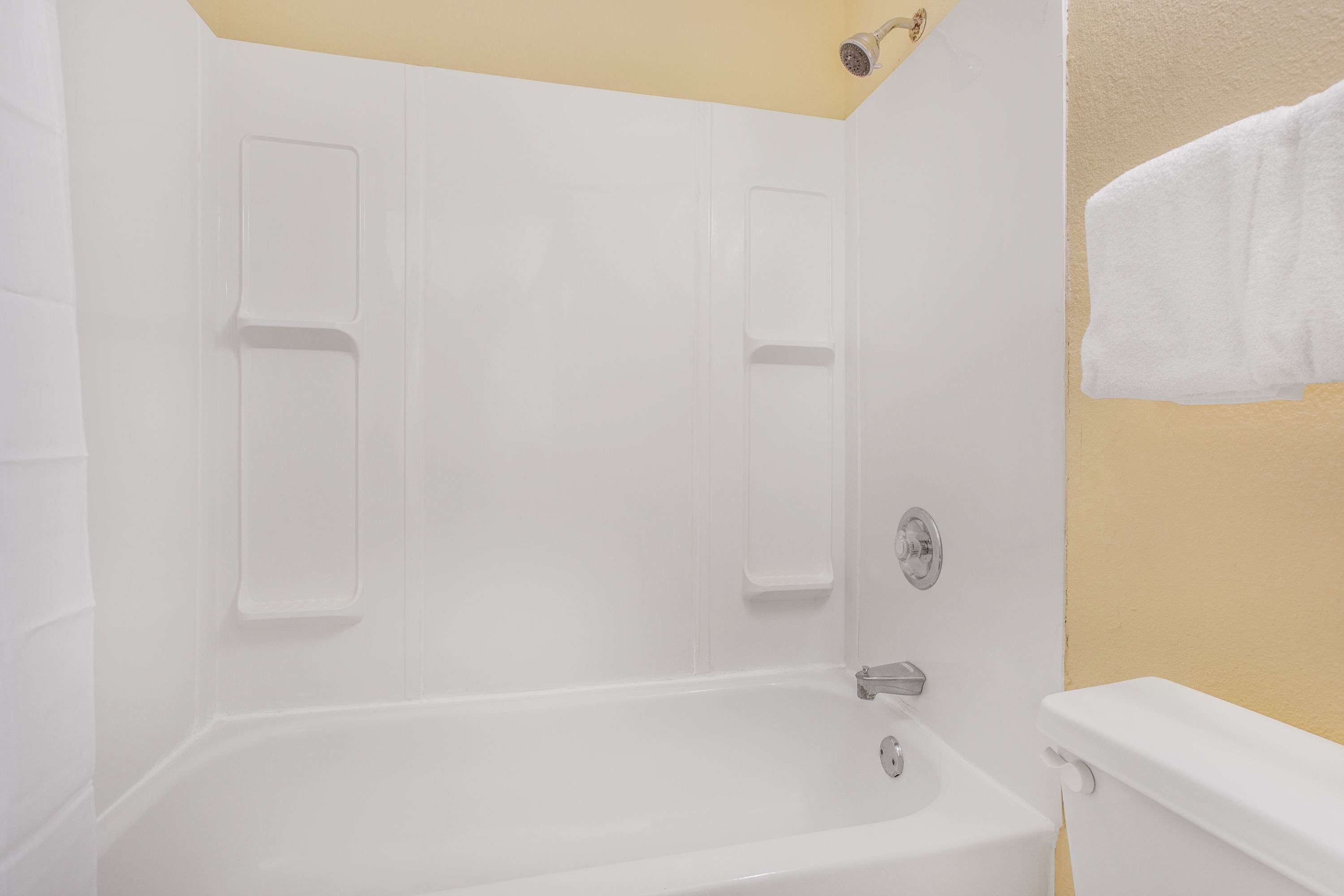 A bathroom with a white bathtub, a shower, and a toilet.