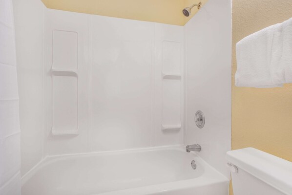 A bathroom with a white bathtub, a shower, and a toilet.