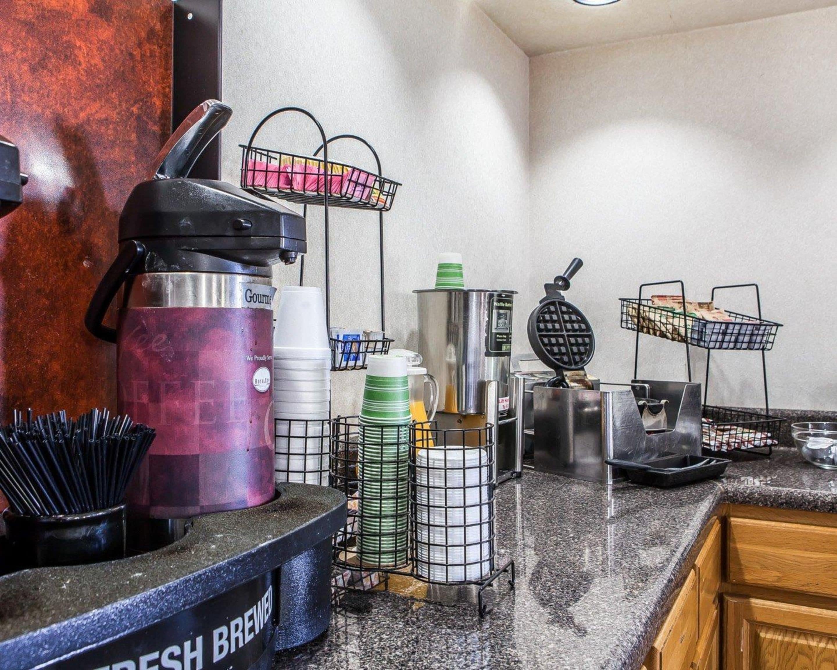 Cozinha equipada com máquina de café, aparelho para waffles e diversos utensílios.