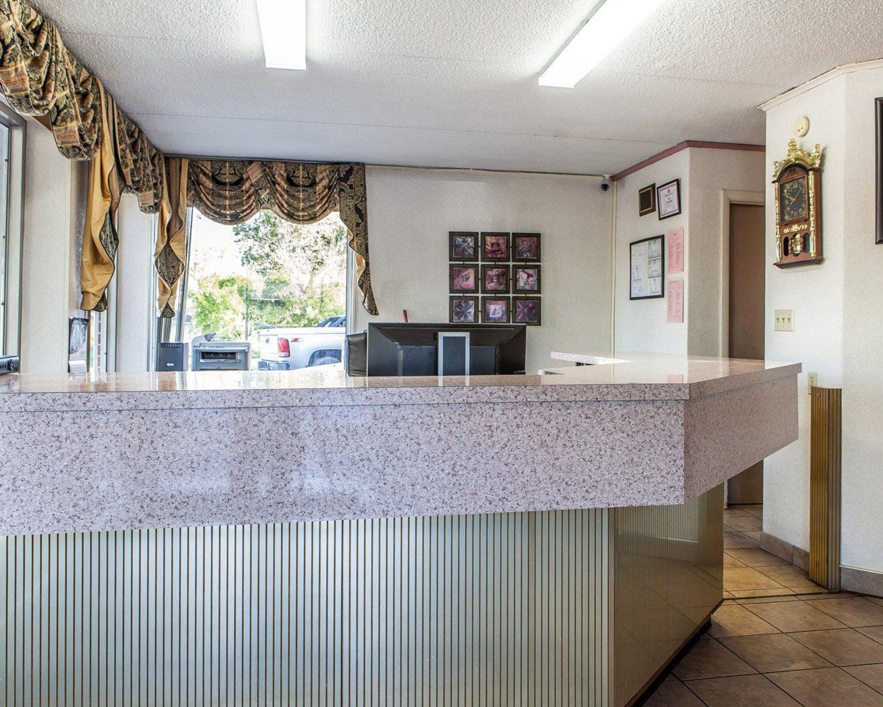 A reception area with a granite counter, framed pictures on the wall, and a clock.