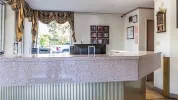 A reception area with a granite counter, framed pictures on the wall, and a clock.