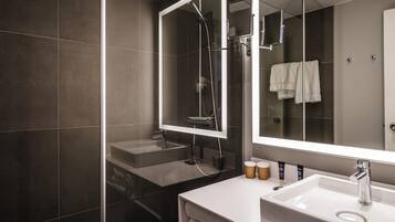 A modern bathroom with a glass-enclosed shower, a large mirror, and a white sink with a vanity.
