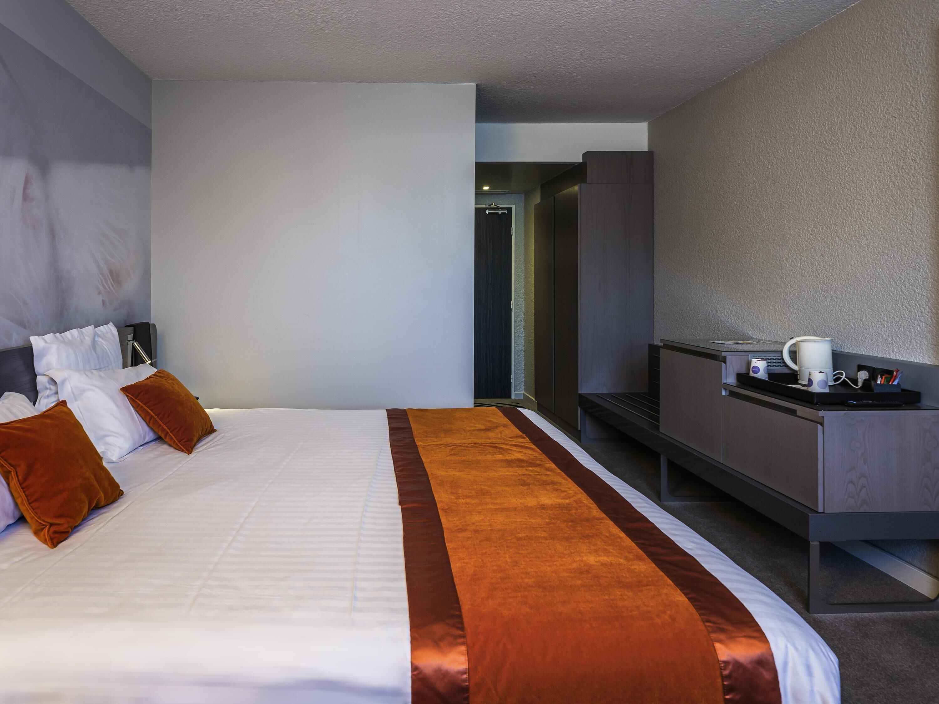Una habitación de hotel con una cama, un escritorio y una cafetera.