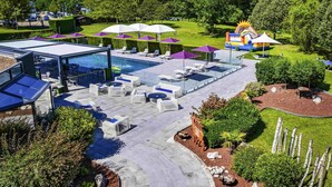 Un área de piscina en la azotea con sillones de descanso, sombrillas y un tobogán.