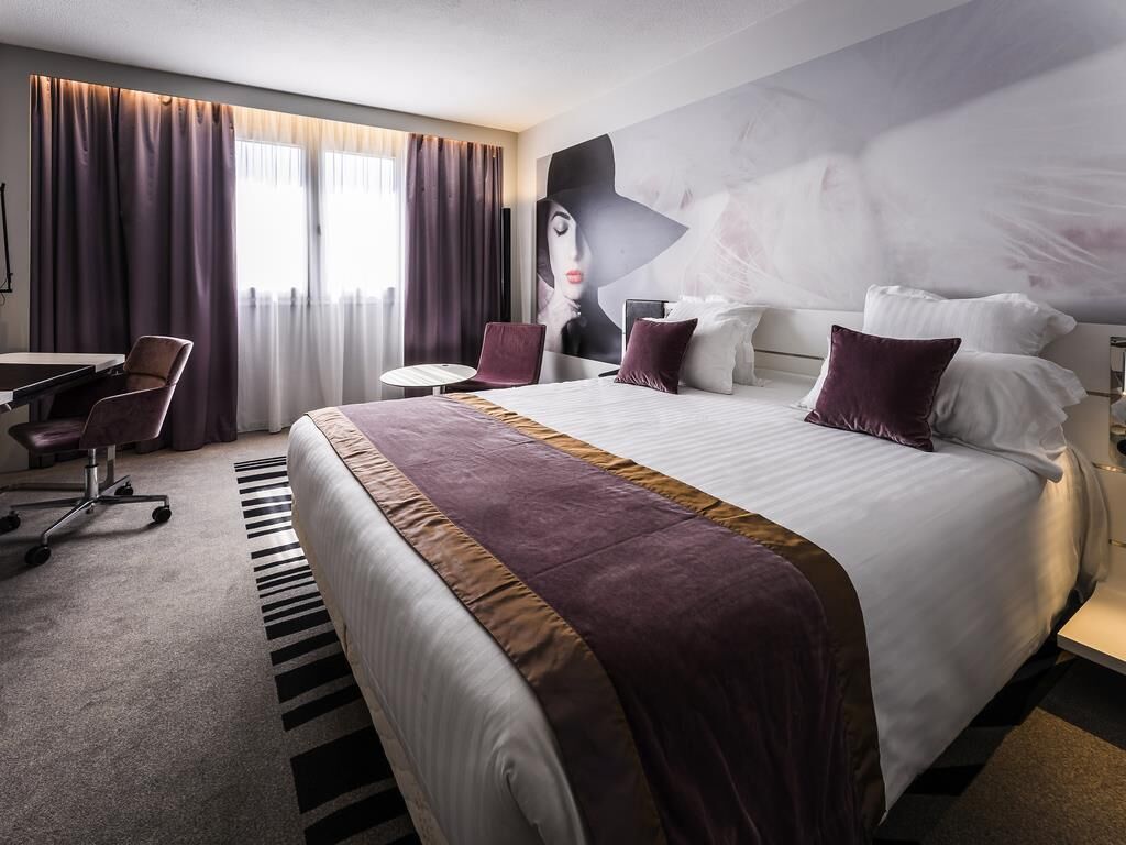 Une chambre d’hôtel avec un grand lit, un bureau, une chaise et une fresque murale.