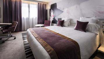 Une chambre d’hôtel avec un grand lit, un bureau, une chaise et une fresque murale.