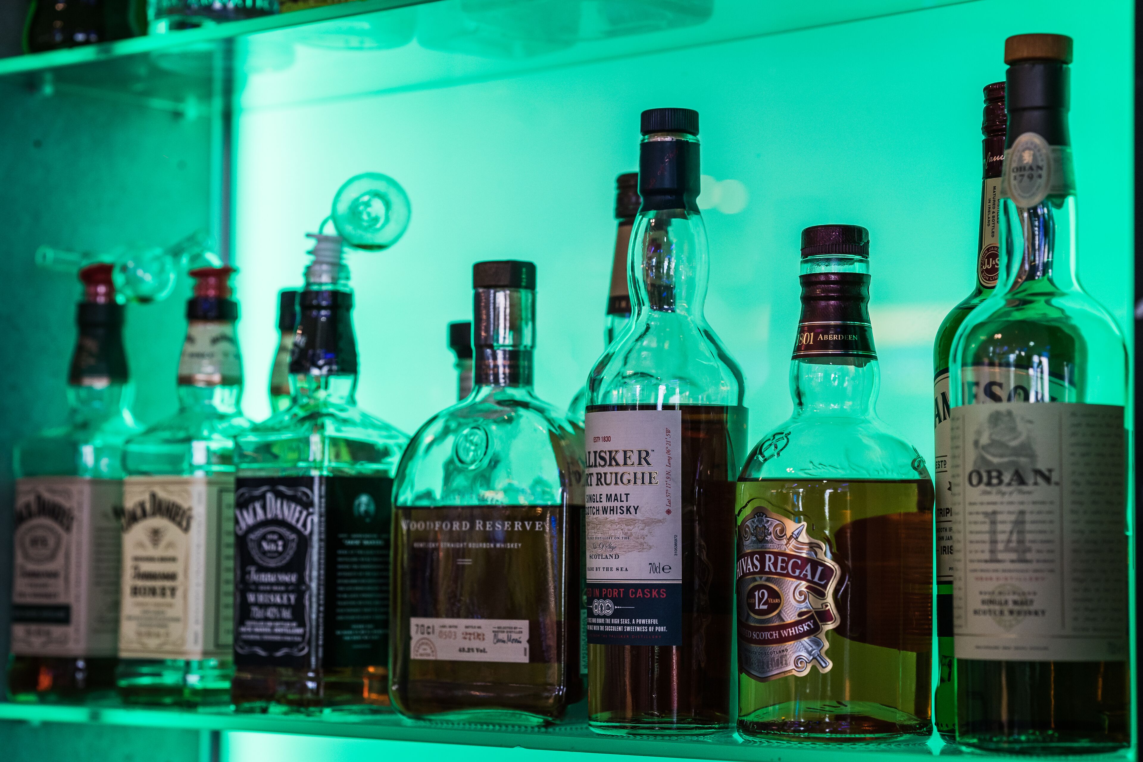 On peut voir une variété de bouteilles de whisky sur une étagère.