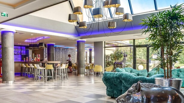 Un vestíbulo de hotel con piso de tablones, zona de bar, asientos y una gran estatua de toro.